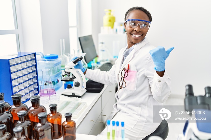 在科学家实验室工作的非洲妇女用拇指指着一边，开心地笑着