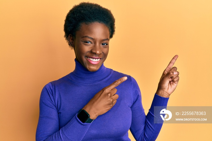 Young african american girl wearing casual clothes smiling and looking at the camera pointing with t