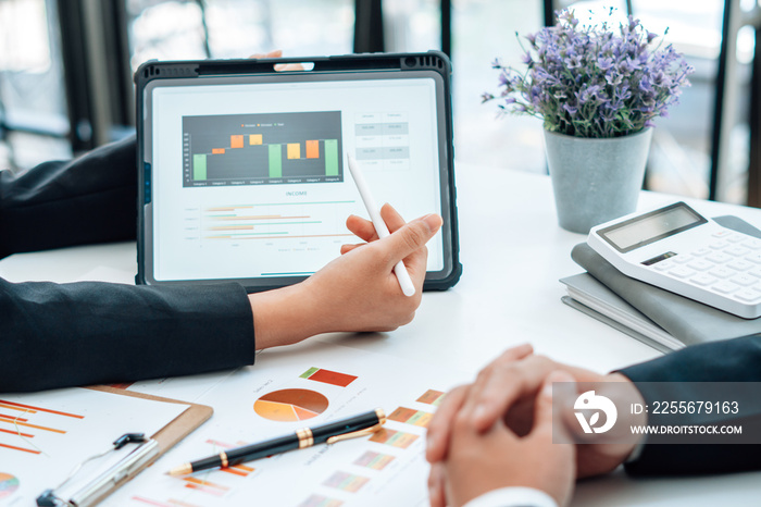 Two businessmen are together analyzing the financial data graph and pointing to the laptop computer 