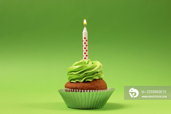 Delicious cupcake with a candle on a colored background with space to insert text. Festive backgroun