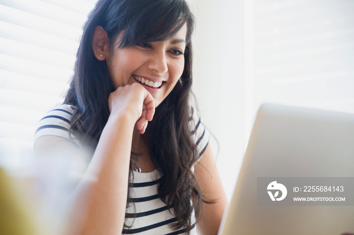 Happy mid adult woman using laptop at home