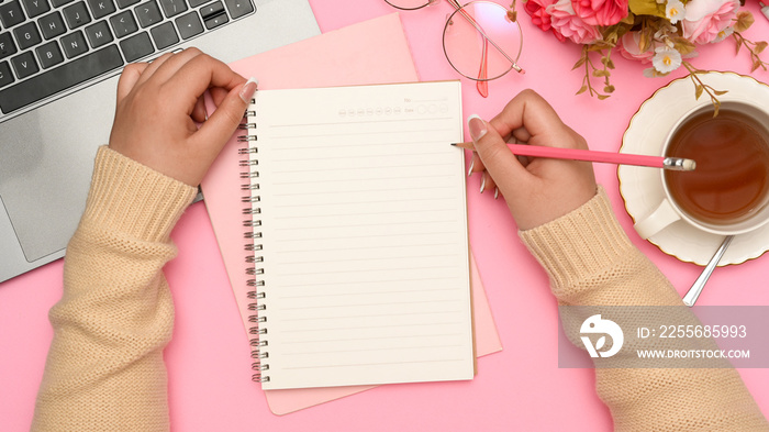 Female college student doing homework, writing essay in her pink desk.