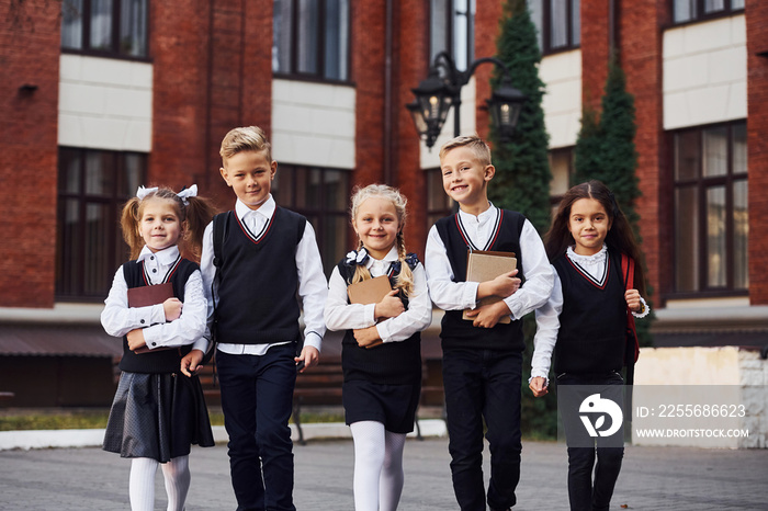 Group of kids in school uniform that is outdoors together near education building