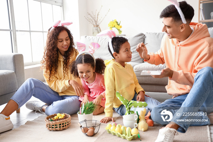 Happy father painting his little sons face at home on Easter day