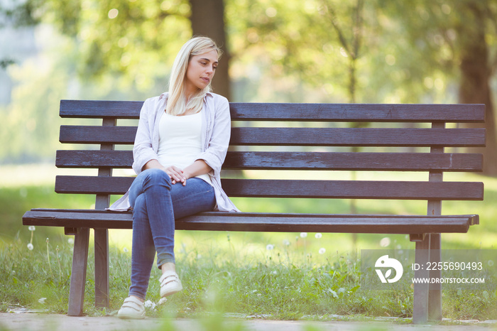 Lonely woman sitting in park in despair.