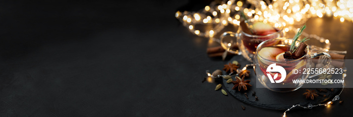 Two cups of Christmas mulled wine with spices and lemon slices on dark wooden background. Christmas 