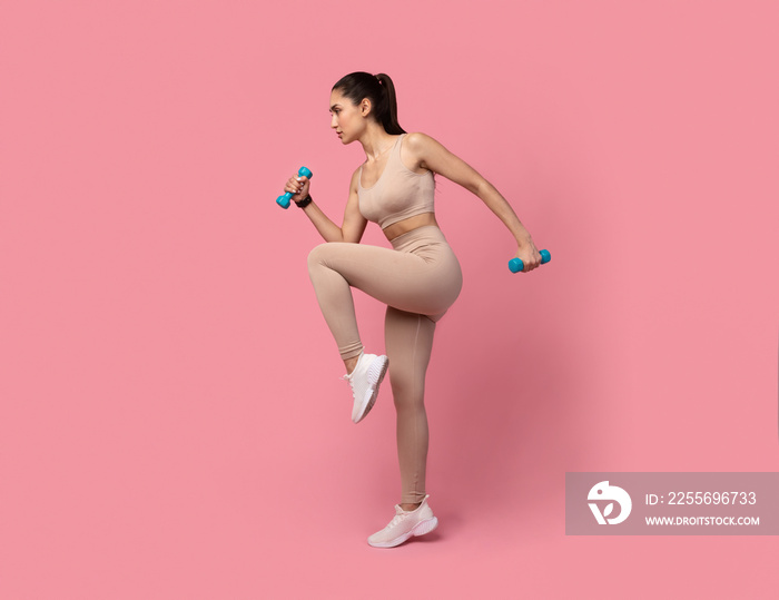 Young Woman Exercising With Dumbbells Isolated On Pastel Background