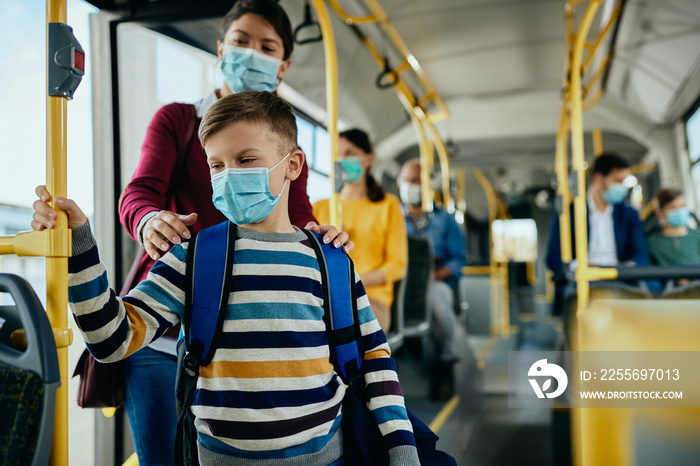 Schoolboy and his mother wearing face masks while getting in a public transport.