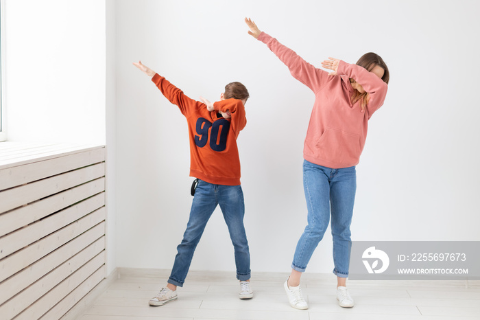Fun, mothers day, children and family concept - teen boy and his mom funny dancing on white backgrou