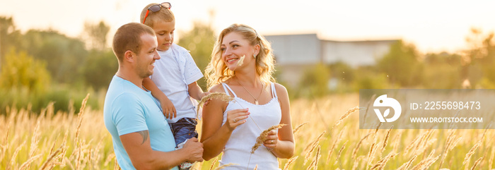 Happy family walking on field in nature at sunset