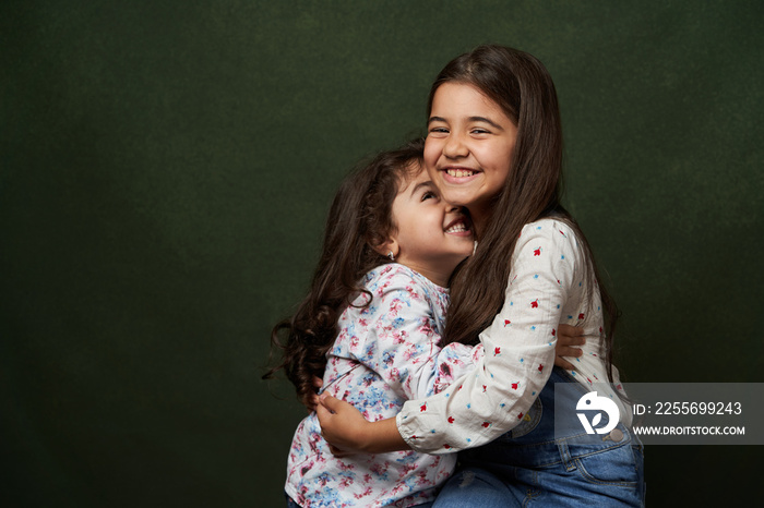 Two sisters portrait on green background with copy space