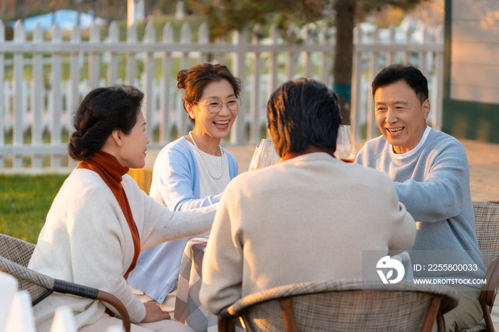 夕阳下中老年朋友在庭院里聚会喝酒聊天