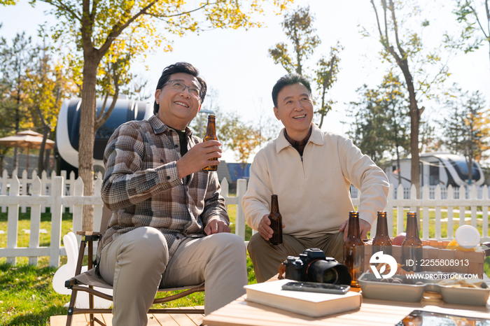 两个老年男人坐在露营地喝啤酒