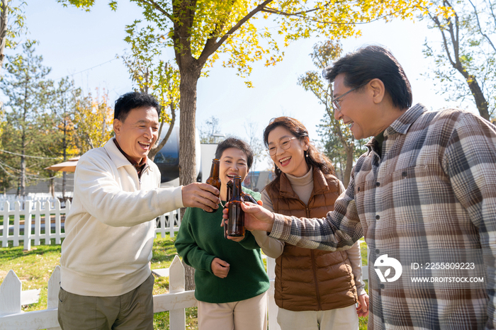 一群中老年人站在房车露营地喝啤酒