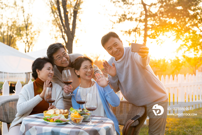 夕阳下中老年朋友在庭院里聚会喝酒拍照片