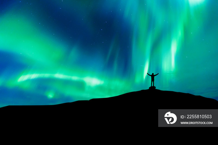 Aurora borealis with silhouette standing man on the mountain.Freedom traveller journey concept