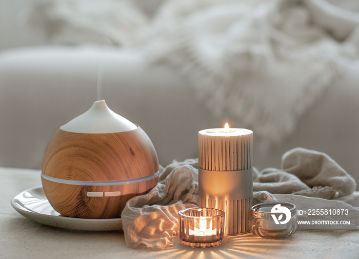 Cozy home composition with air humidifier and candles on blurred background.