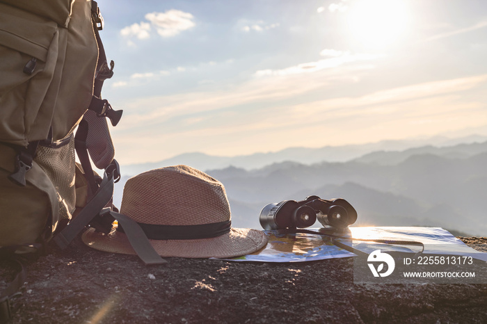 binoculars and map and hat and backpack on the rock mountains.