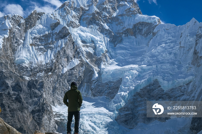 hiker fulfilling goal in the mountain, success, happiness. in front of an impressive mountain covered with ice and snow on the way to the everest base camp. himalayan mountains. active sport, overcomi