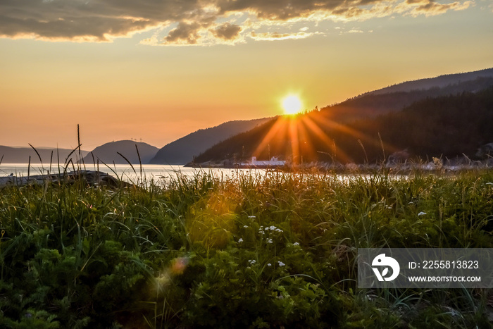 beautiful sunset over Tadoussac bay and grassy field