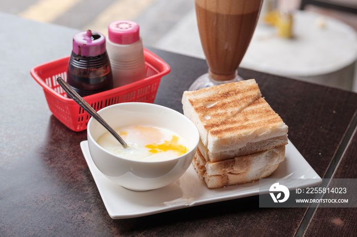Kaya Toast, Coffee bread and Half-boiled eggs Singapore breakfast. Iced coffee and bread toast with a local jam made from eggs, sugar and coconut milk.