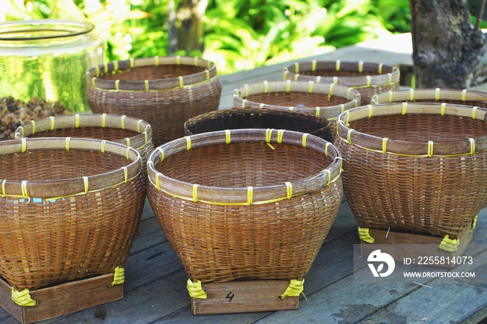 Vintage handwoven bamboo baskets displayed on an outdoor table with sunny tropical foliage in the background