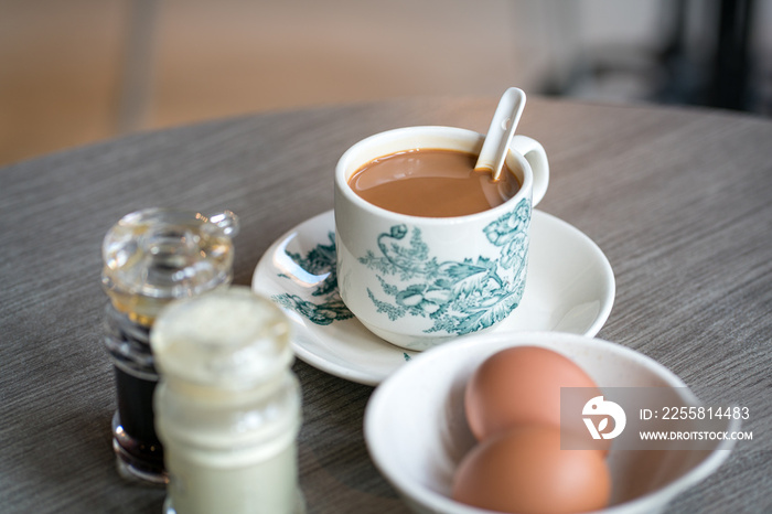 Coffee with boiled eggs, soy sauce and white pepper on table. Traditional oriental Chinese kopitiam style morning breakfast.