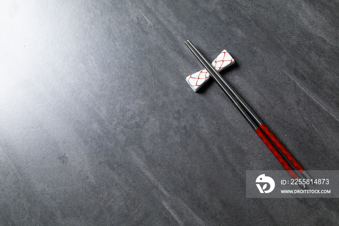 Steel chopsticks with holder on black stone background. Chinese Traditional cuisine concept. Dumplings Dim Sum in bamboo steamer with text copy space. Asian food background