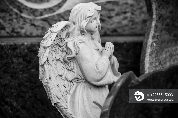 closeup of stoned angel praying on tomb at cemetery