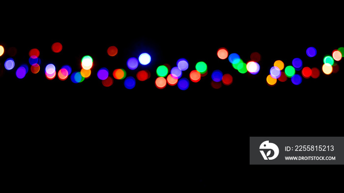 Festive Christmas and New Year background with defocused multicolored lights garland on black background, copy space