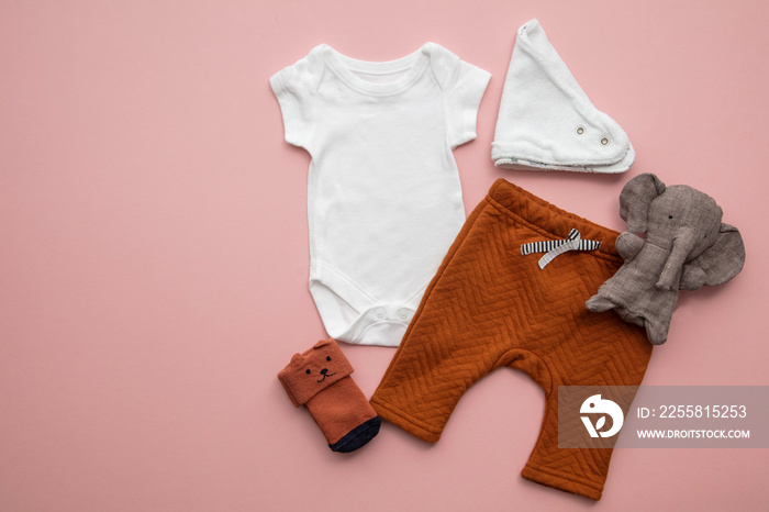 Newborn child clothing layout on a pastel pink background