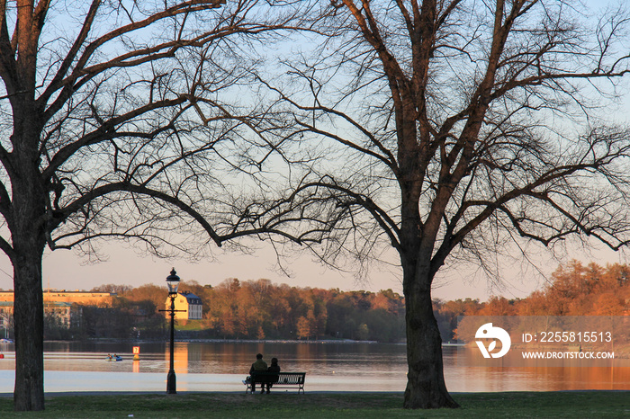 Silhouette of a couple sitting on a bench at the lakeside at sunset