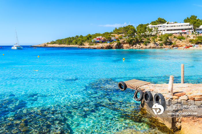 Small pier and view of azure blue sea in  Cala Portinatx bay, Ibiza island, Spain