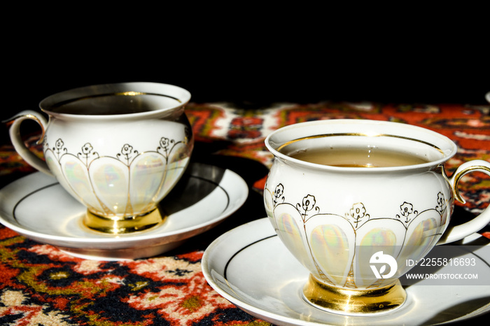 Two vintage porcelain cups of coffee or tea on the oriental turkish or asian carpet, tea ceremony