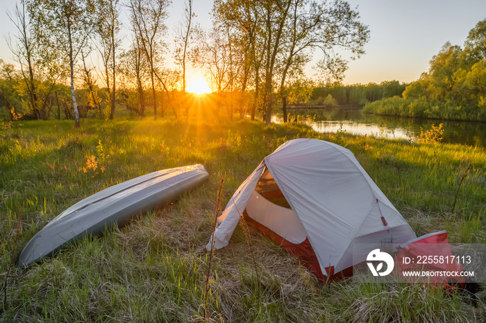 Landscape with camping tent and kayak on the river at sunrise