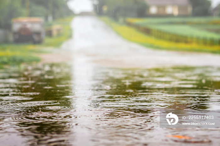 Puddle with water on the road during the shower. Strong rain on summer day_