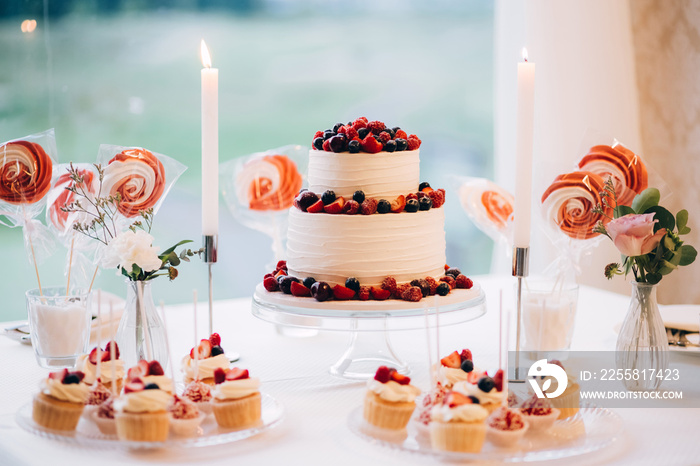 Beautiful cake covered with icing cream, summer berries on the top. Style and food photography