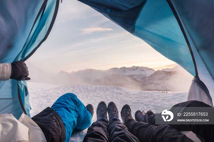 Group of climber are inside a tent with open for view of blizzard on mountain