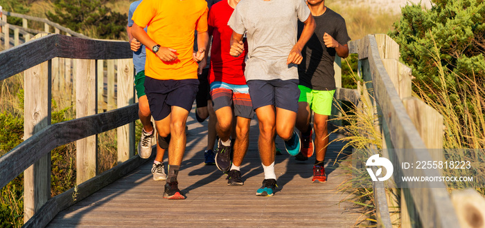 Group of teenagers running on a boardwalk in sunshine