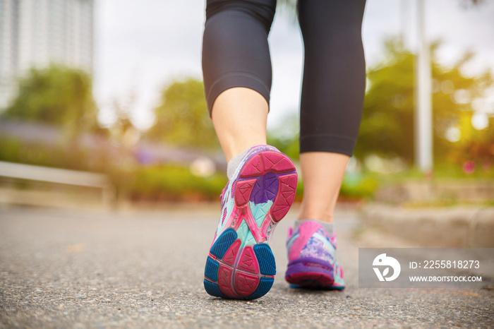 Close up on shoe, Runner athlete feet running on road under sunlight in the morning.