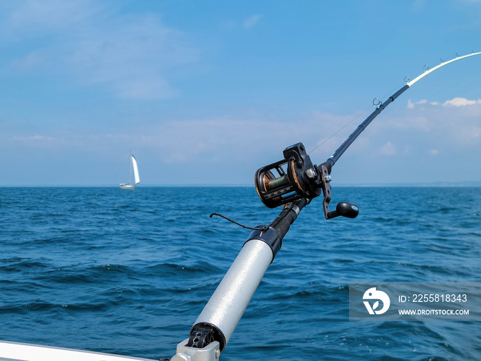 Fishing pole in a rod holder with sailboat in the background