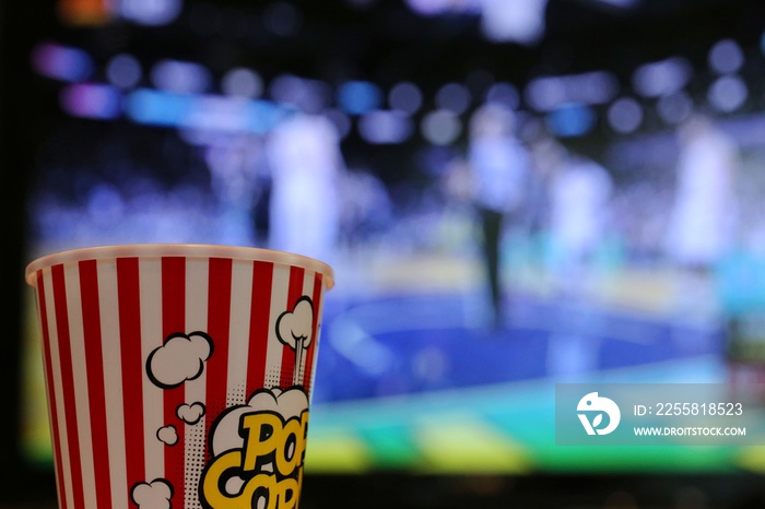 Cup of popcorn closeup blur TV screen background