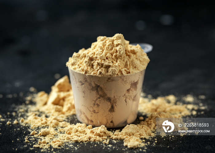 Scoop of Pea Vegan protein powder on dark rustic background. Sport nutrition.