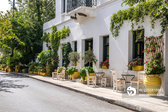 Greek outdoors cafe, table and chair on pavement at Kythera island Milopotamos. Pots with flowers.