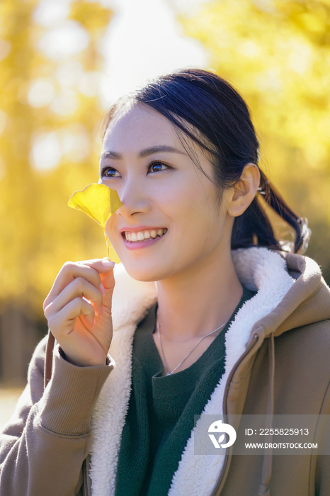 快乐的年轻女子手拿银杏叶