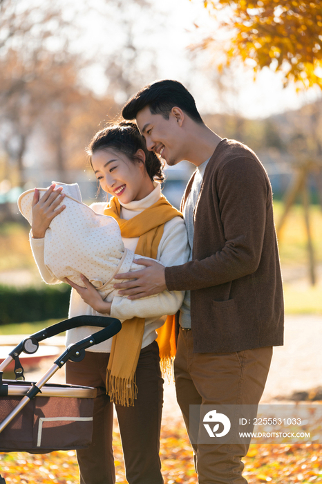 年轻夫妻推着婴儿车散步