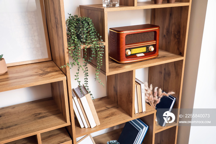 Modern shelf unit with books and retro radio receiver, closeup