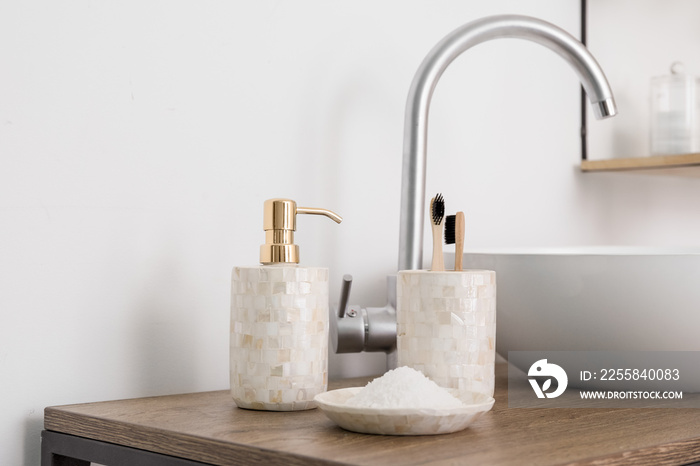 Bath accessories on table near white wall, closeup