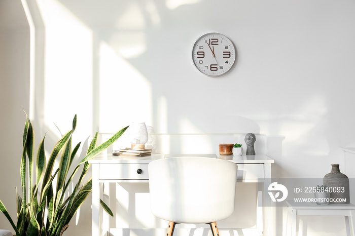 Modern workplace and clock hanging on light wall