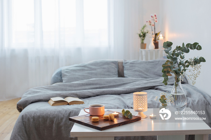 interior of bedroom with bouquet, candles and cup of tea